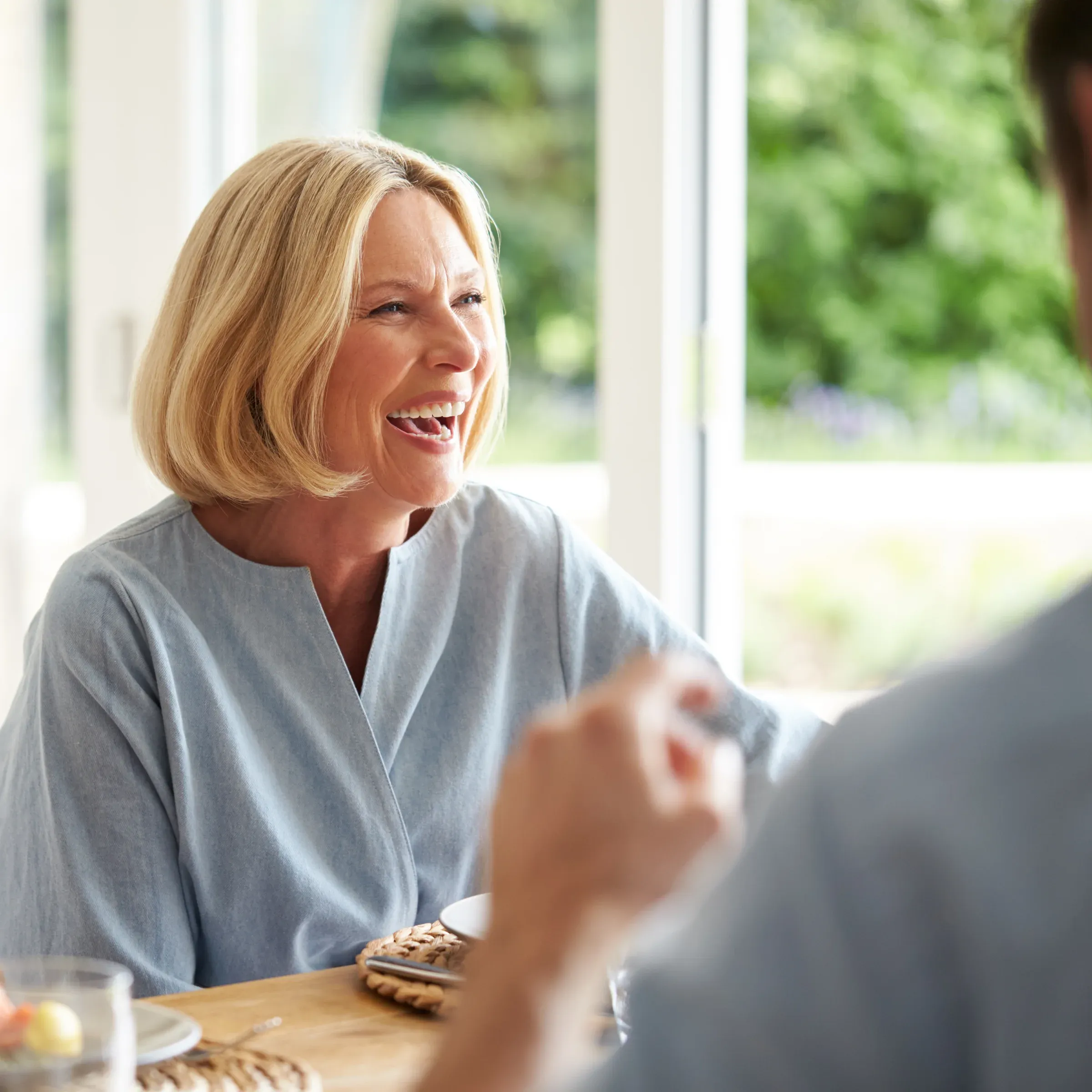 Lachende Frau im Gespräch an einem Tisch
